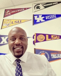 a man in a tie standing in front of a wall full of pennants