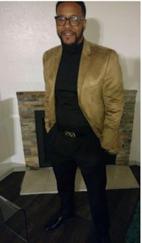 a man wearing a tan blazer and black pants