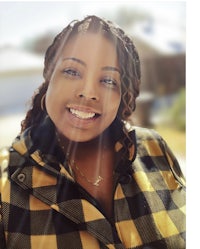 a black woman wearing a yellow and black plaid jacket