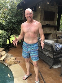 a bald man standing next to a pool